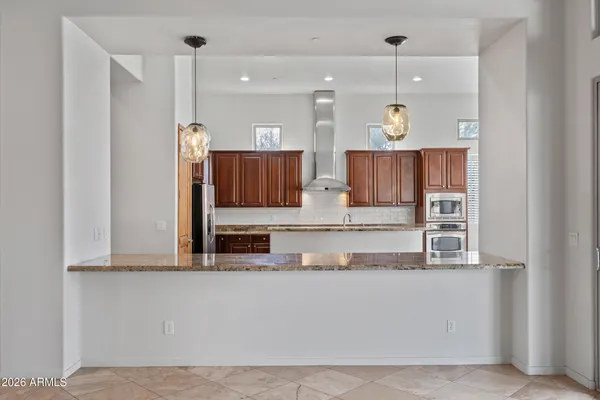 a kitchen with stainless steel appliances kitchen island granite countertop a refrigerator and wooden cabinets