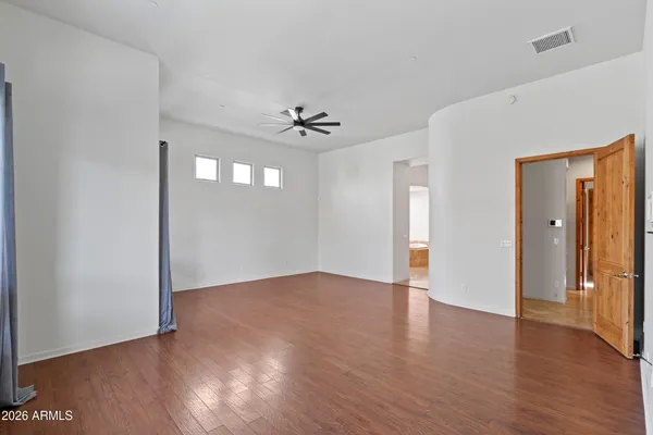 an empty room with wooden floor and a ceiling fan