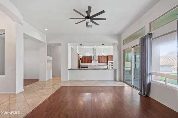 a view of a big room with wooden floor a ceiling fan and windows