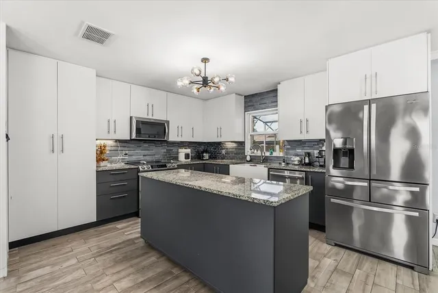 a kitchen with kitchen island granite countertop stainless steel appliances cabinets a sink and a center island