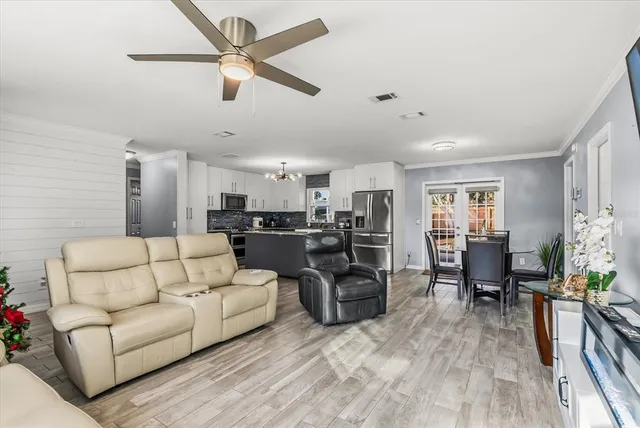 a living room with furniture kitchen view and a wooden floor