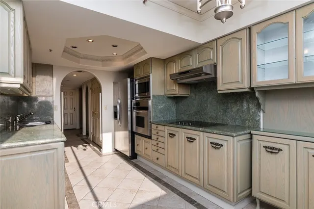 a kitchen with stainless steel appliances granite countertop a refrigerator a stove and a sink with wooden cabinets