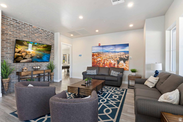 2600 Ocotillo Way, Unit 31 Santa Clara, UT 84765 - Photo 57 of 73 Spacious living area featuring a prominent exposed brick accent wall, recessed lighting, wood-finish flooring, and multiple windows for natural illumination