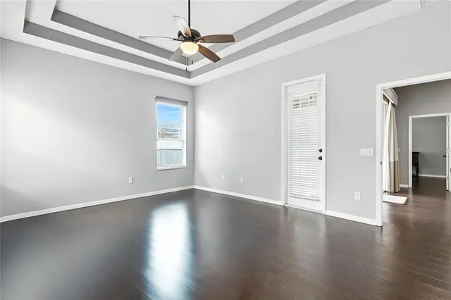 a view of an empty room with wooden floor and a ceiling fan