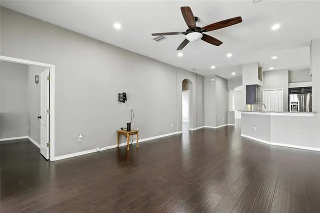 a view of empty room with wooden floor and ceiling fan