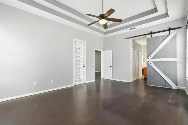 an empty room with wooden floor and ceiling fan