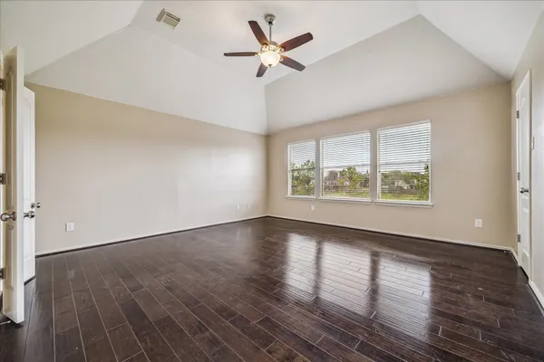 an empty room with wooden floor chandelier fan and windows