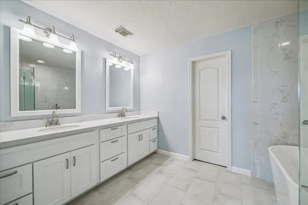 a spacious bathroom with a double vanity sink mirror and bathtub