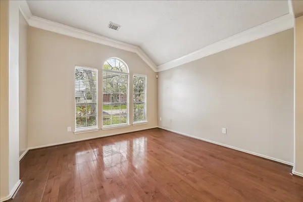 an empty room with wooden floor and windows
