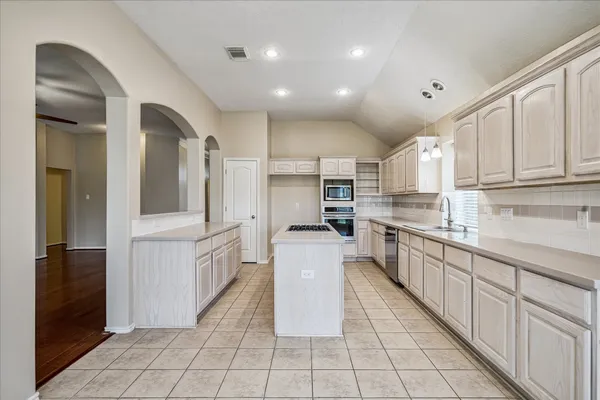 a large kitchen with stainless steel appliances lots of counter space and wooden floor