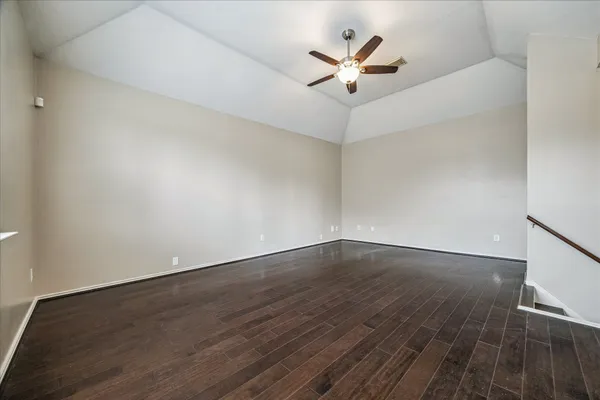 an empty room with wooden floor and ceiling fan