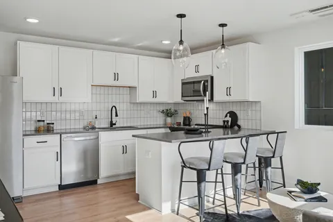 a kitchen with stainless steel appliances a white table chairs refrigerator and sink