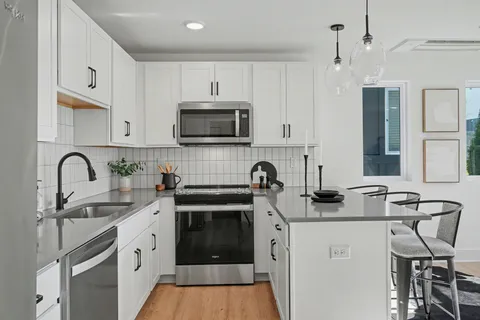 a kitchen with stainless steel appliances a sink a stove a microwave a sink a refrigerator and cabinets