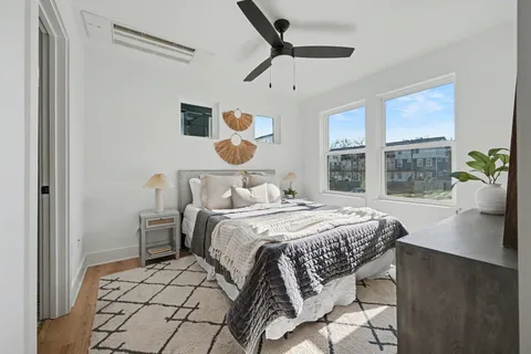 a bedroom with a bed and ceiling fan with a large window