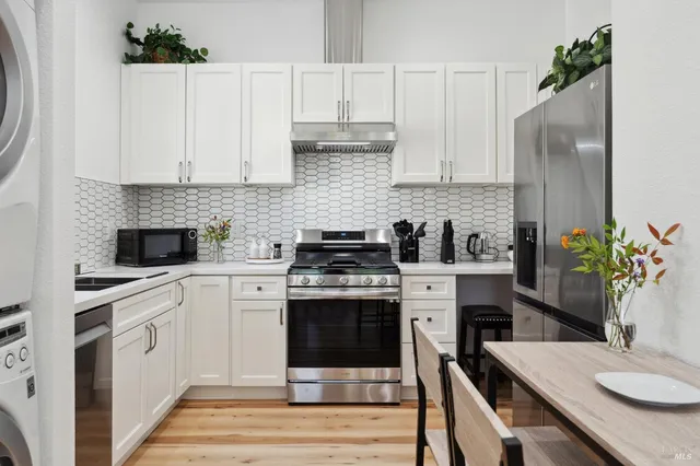 a kitchen with white cabinets stainless steel appliances and a potted plant
