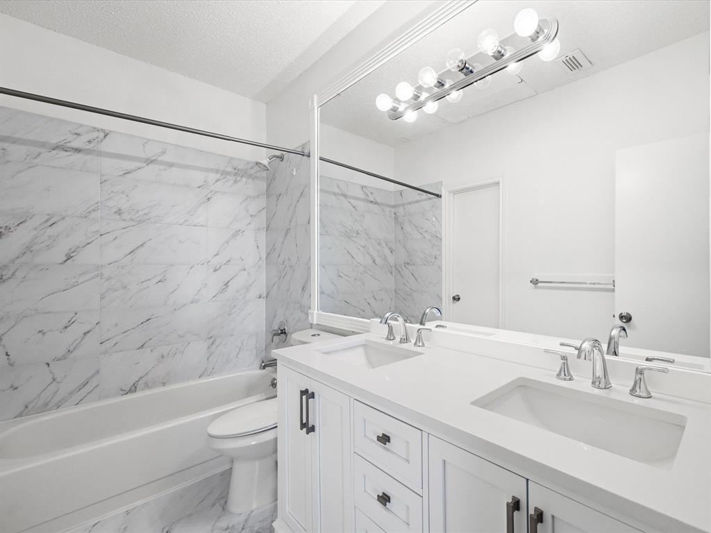 5310 Keller Springs Road, Unit 332 Dallas, TX 75248 - Photo 9 of 39 Bathroom with light marble finish floors, double vanity, shower combination, and a textured ceiling