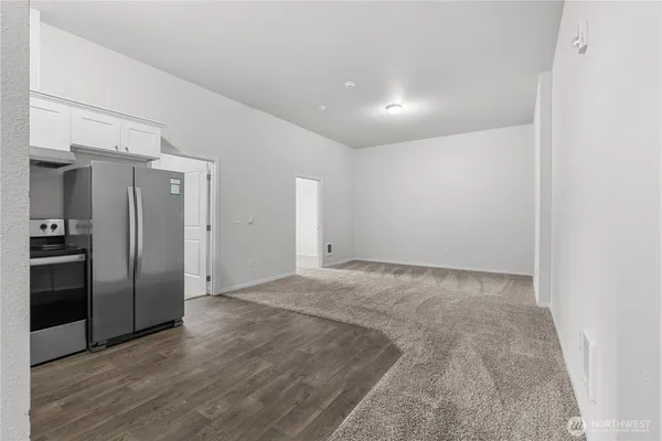 a view of a kitchen with a refrigerator wooden floor and a window