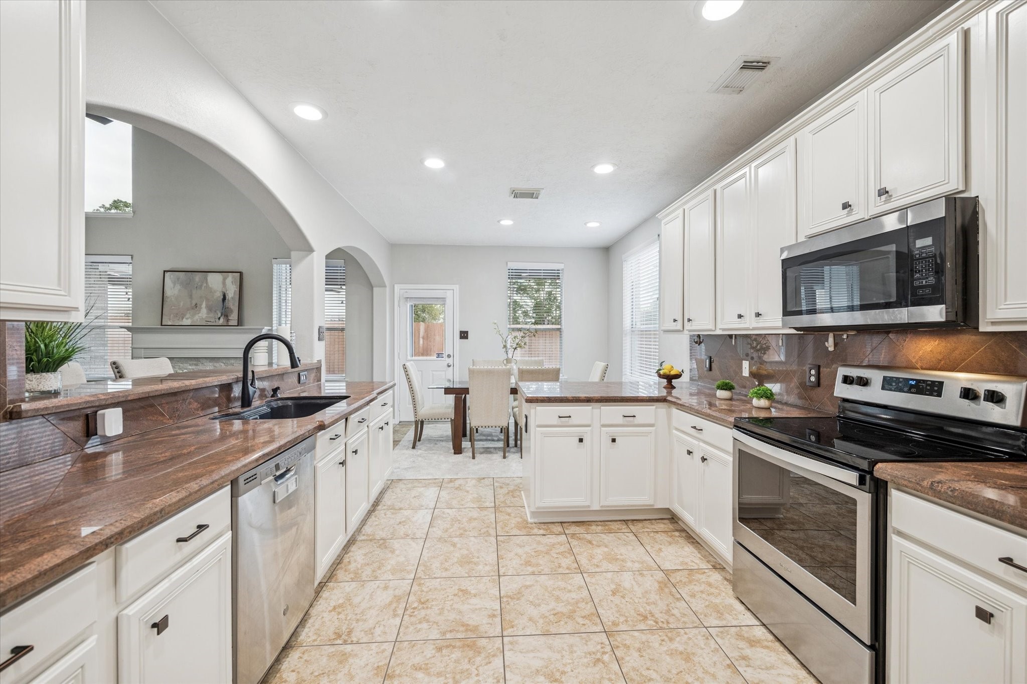 7243 Emerald Run Lane Spring, TX 77379 - Photo 16 of 35 a large kitchen with stainless steel appliances granite countertop a sink and dishwasher a stove top oven with white cabinets