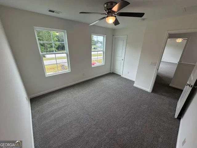 an empty room with windows and fan