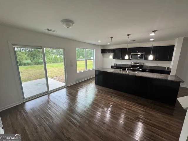 a kitchen with stainless steel appliances granite countertop a sink a stove and wooden floors