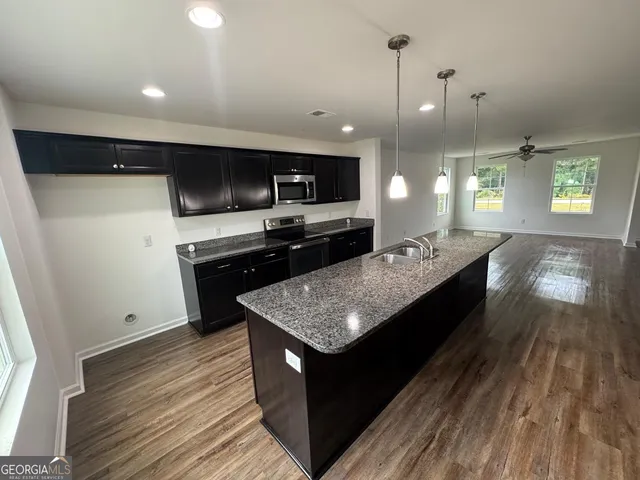 a large kitchen with a sink a counter space and stainless steel appliances