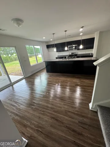 a kitchen with stainless steel appliances kitchen island granite countertop a stove window and wooden floor