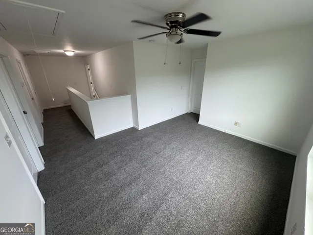 an empty room with a ceiling fan and carpet