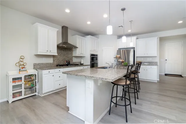 a kitchen with stainless steel appliances kitchen island granite countertop a refrigerator and a sink