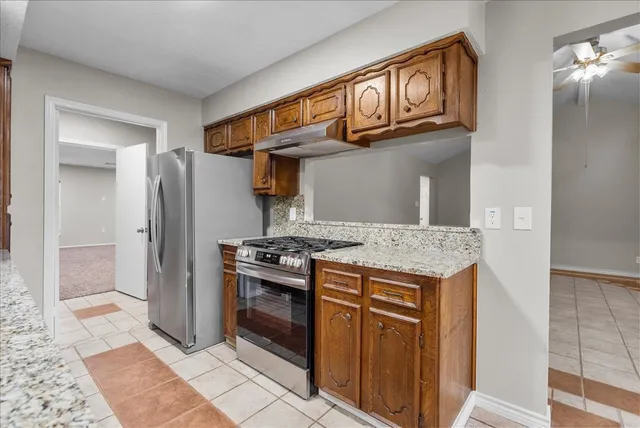a kitchen with stainless steel appliances granite countertop a stove a refrigerator and a cabinets