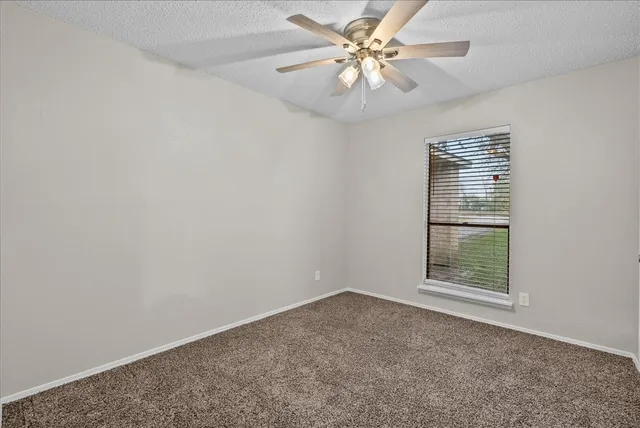 an empty room with a window and a ceiling fan