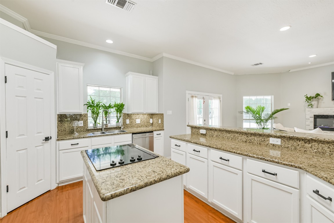 6002 Ranch Park Road Magnolia, TX 77354 - Photo 10 of 49 This bright kitchen features granite countertops, an island cooktop, and ample white cabinetry. It opens into a co living area with a fireplace.