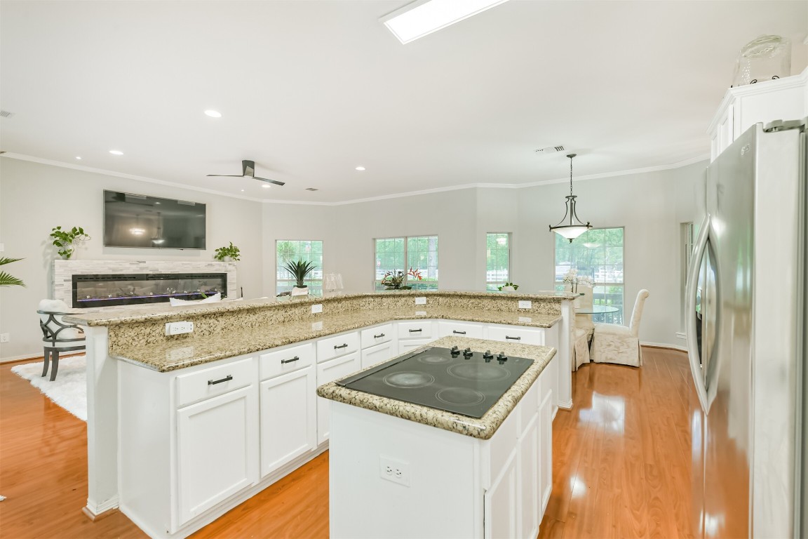 6002 Ranch Park Road Magnolia, TX 77354 - Photo 11 of 49 This photo showcases a spacious, open-concept kitchen and living area with modern appliances, granite countertops, and ample natural light. The kitchen island features a cooktop and plenty of storage.