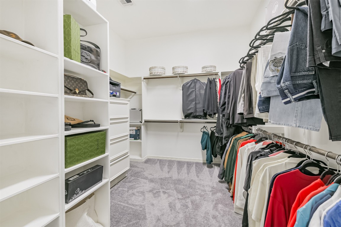6002 Ranch Park Road Magnolia, TX 77354 - Photo 20 of 49 Spacious walk-in closet with ample shelving and hanging space, featuring built-in drawers and carpeted flooring for a luxurious feel.