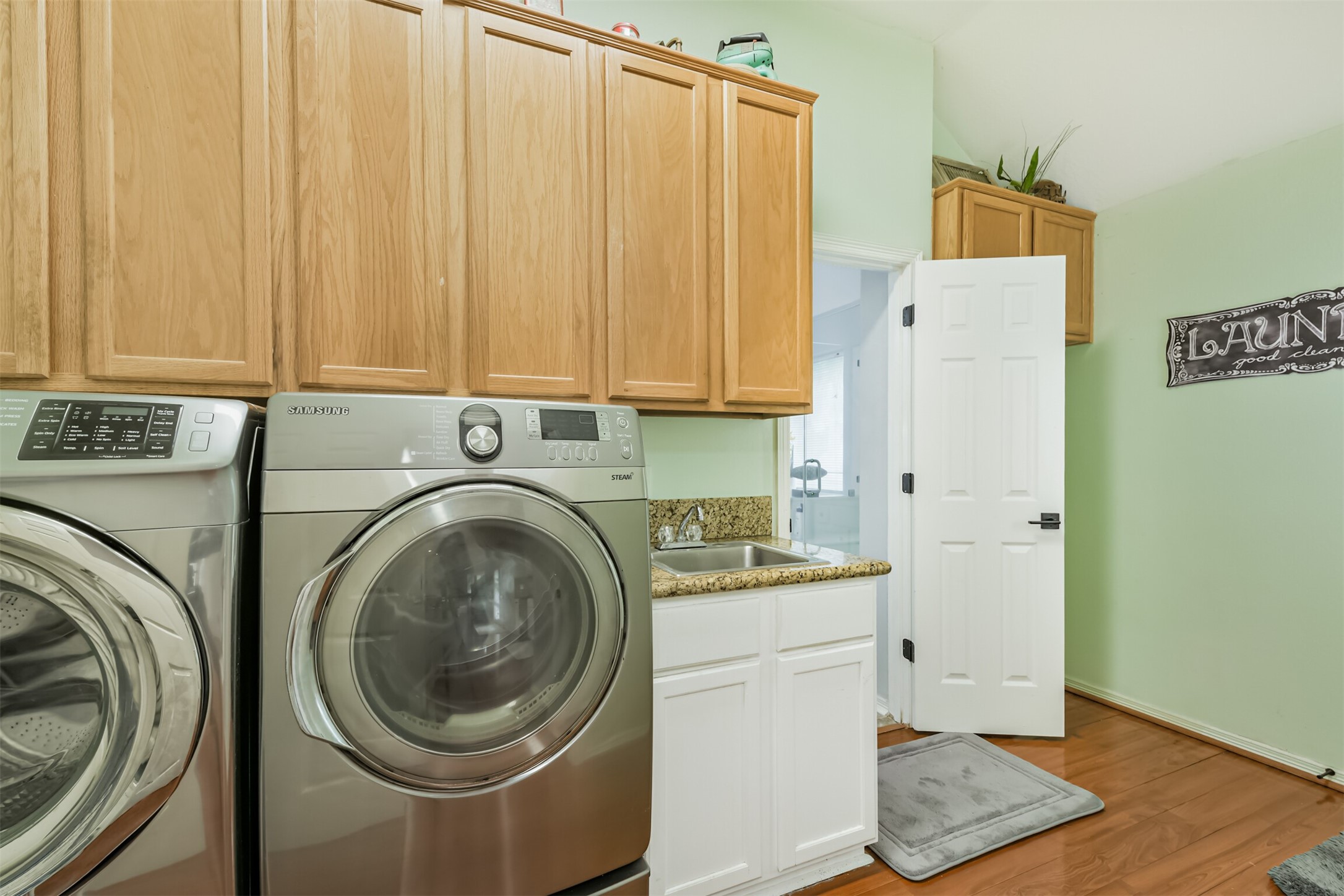6002 Ranch Park Road Magnolia, TX 77354 - Photo 26 of 49 This laundry room features modern stainless steel appliances, ample wooden cabinetry, a granite countertop with a sink.