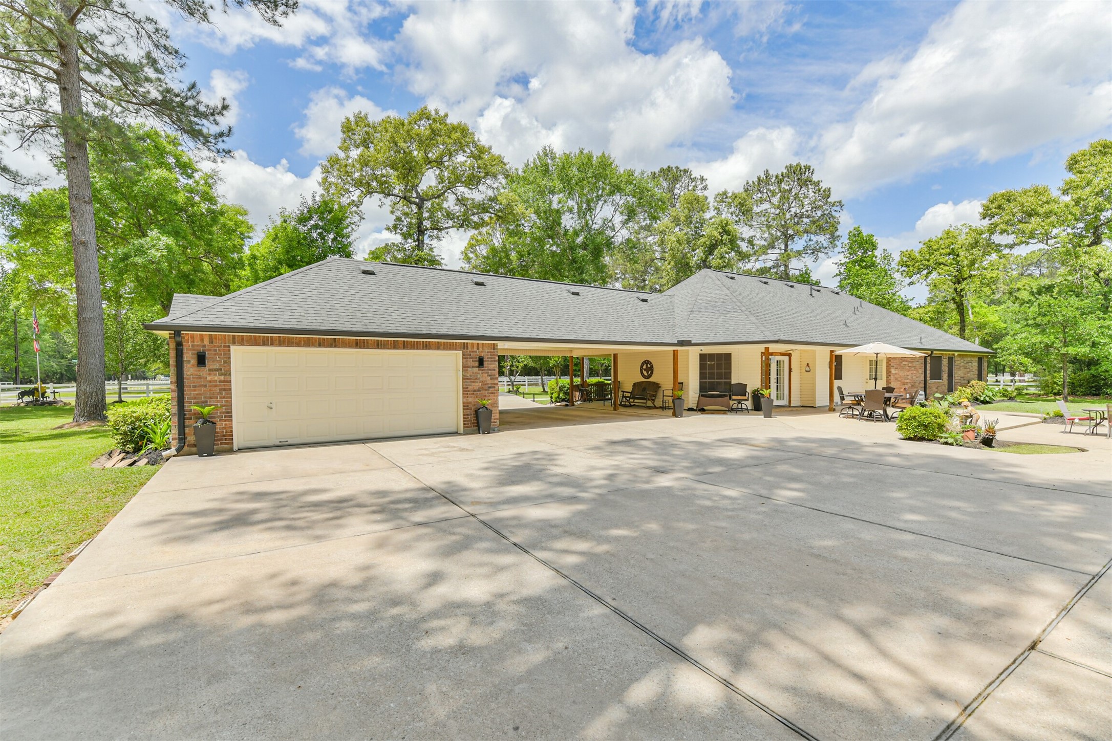 6002 Ranch Park Road Magnolia, TX 77354 - Photo 30 of 49 This photo showcases a spacious, single-story home with a large driveway and attached garage. The property features a well-maintained exterior, surrounded by lush greenery and mature trees, offering a peaceful and inviting atmosphere.