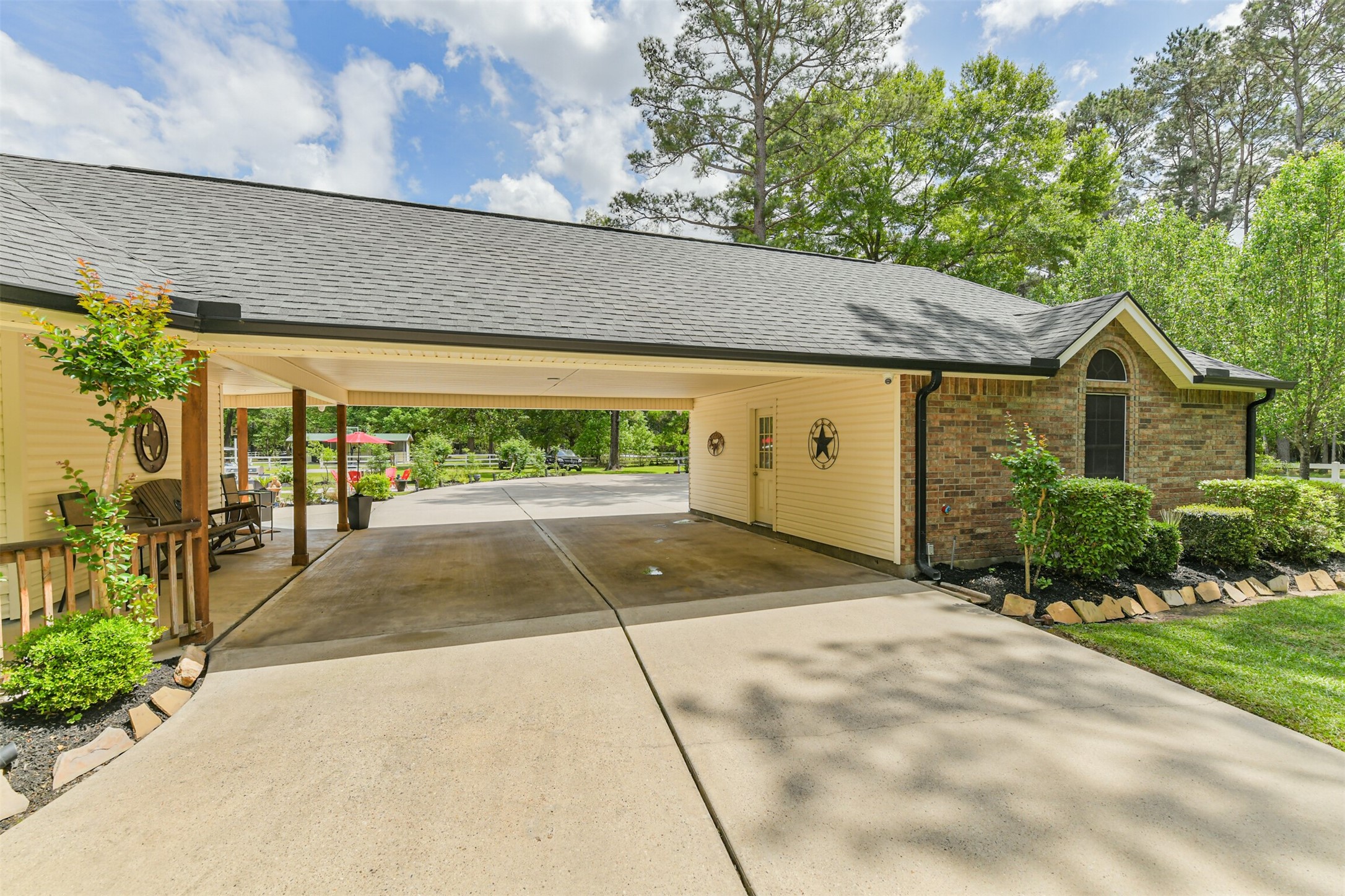 6002 Ranch Park Road Magnolia, TX 77354 - Photo 33 of 49 This photo showcases a well-maintained home with a spacious carport for extra parking. The driveway is wide, and the surrounding trees provide a serene, natural setting.