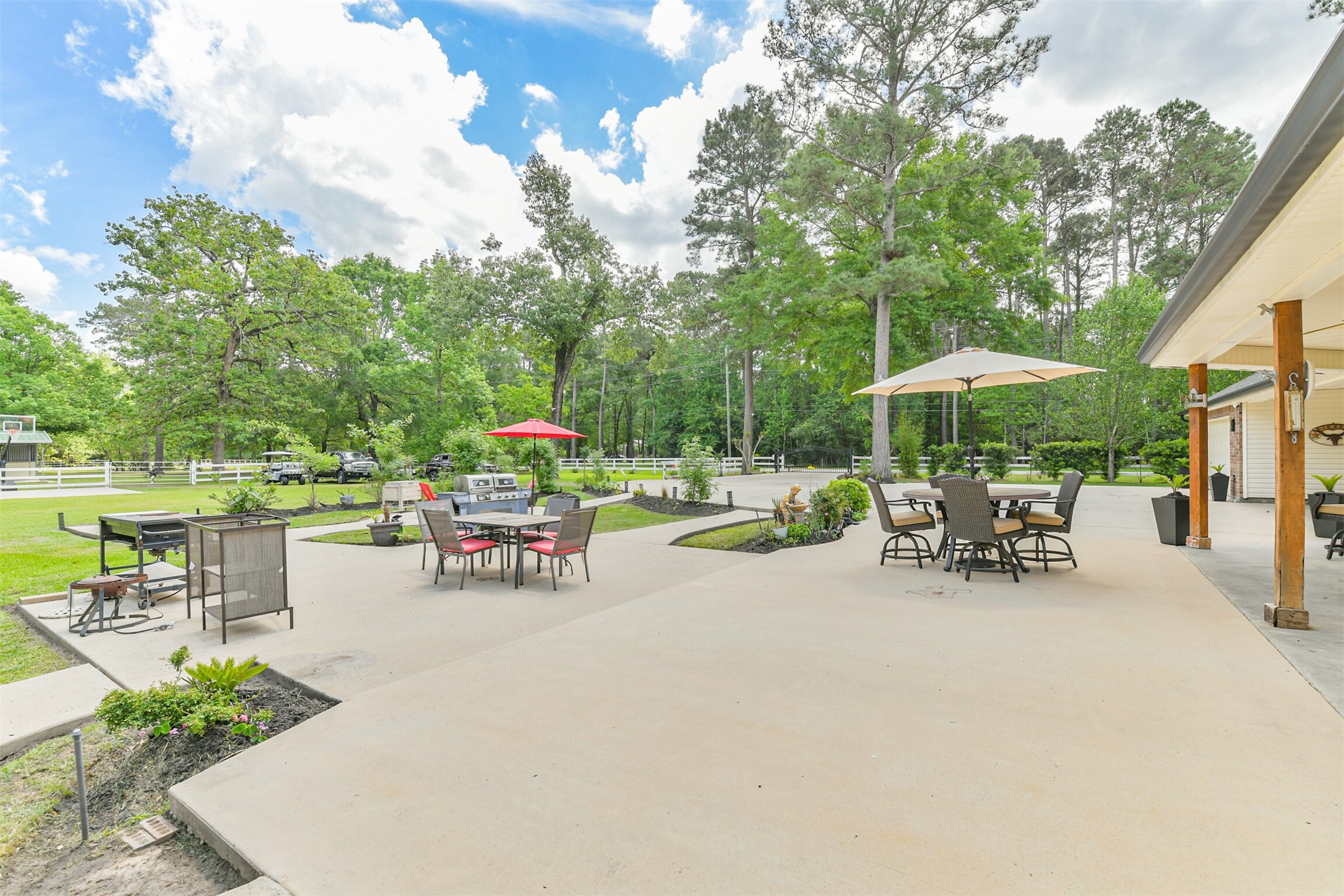 6002 Ranch Park Road Magnolia, TX 77354 - Photo 35 of 49 Spacious outdoor patio with multiple seating areas and umbrellas, surrounded by greenery and trees. Ideal for entertaining and relaxation.