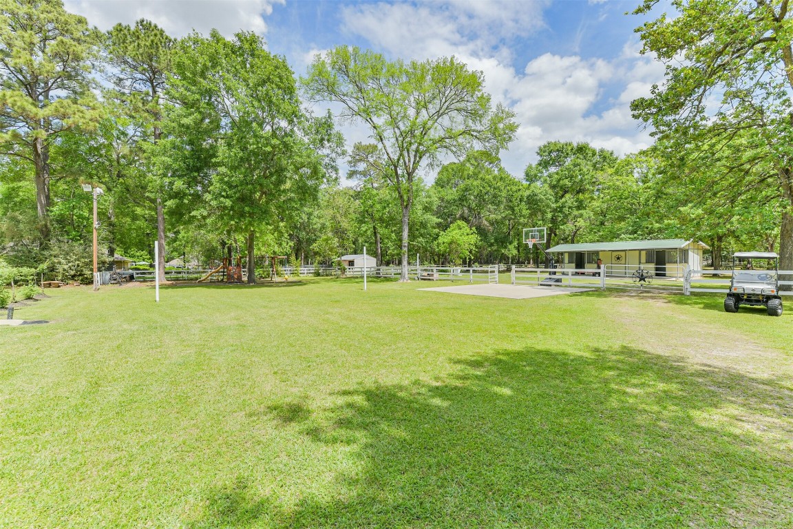 6002 Ranch Park Road Magnolia, TX 77354 - Photo 39 of 49 Expansive grassy yard with mature trees, a basketball court, and a 37x22 Two- Stall Barn. Ideal for outdoor activities and relaxation in a peaceful, natural setting.