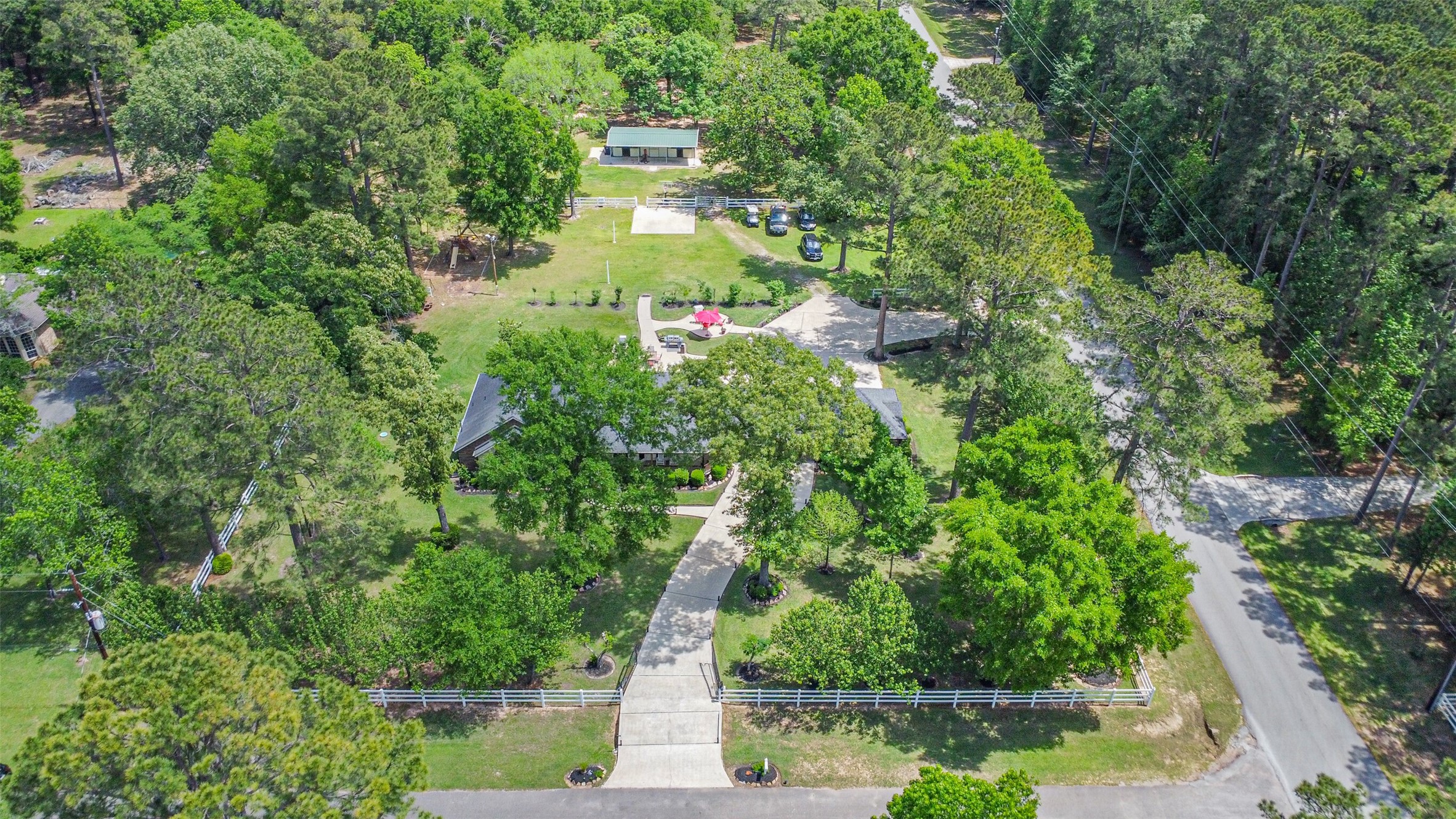 6002 Ranch Park Road Magnolia, TX 77354 - Photo 43 of 49 This aerial view showcases a spacious property surrounded by lush greenery and mature trees, offering a private and serene setting. The home features a long driveway, ample outdoor space, and a charming patio area, ideal for relaxation or entertaining.