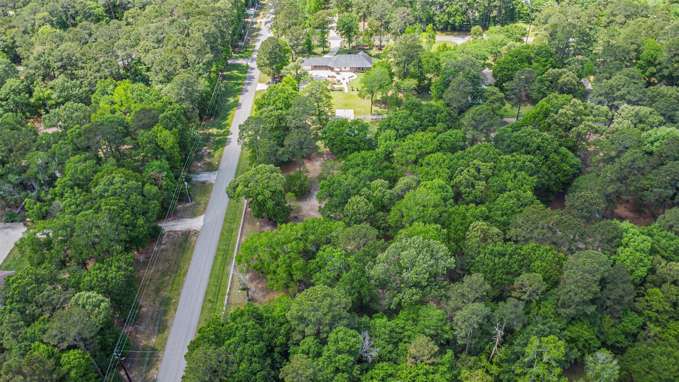 6002 Ranch Park Road Magnolia, TX 77354 - Photo 46 of 49 This aerial photo showcases a serene, wooded neighborhood with lush greenery. A paved road runs through the area, offering privacy and a natural setting. Ideal for nature lovers seeking tranquility.
