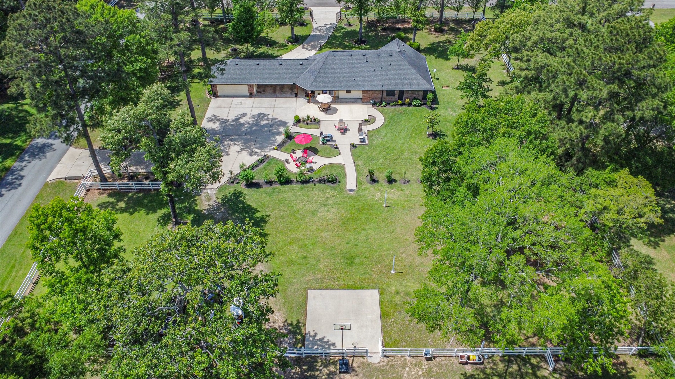 6002 Ranch Park Road Magnolia, TX 77354 - Photo 48 of 49 This aerial view showcases a spacious property with a single-story home, expansive driveway, and a well-maintained yard surrounded by lush greenery and mature trees, offering a serene and private setting ideal for family living and outdoor activities.