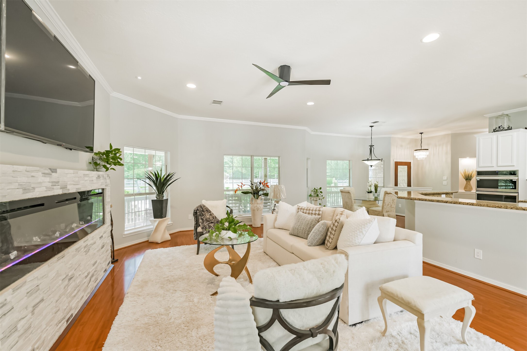 6002 Ranch Park Road Magnolia, TX 77354 - Photo 49 of 49 This spacious living area features an open floor plan with a modern fireplace, large windows for natural light. The contemporary kitchen with a breakfast bar seamlessly connects to the dining space, creating a cozy and inviting atmosphere.