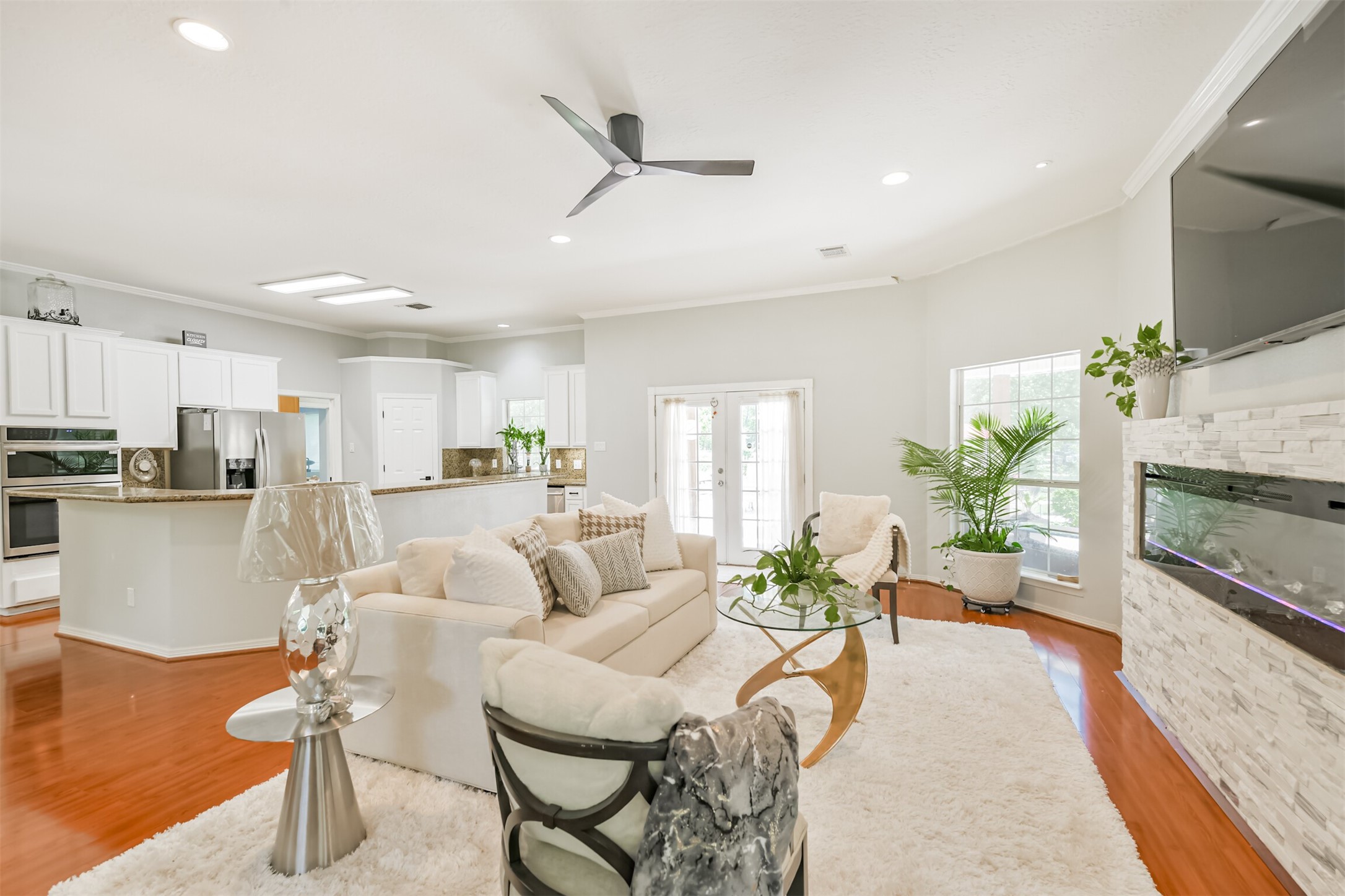 6002 Ranch Park Road Magnolia, TX 77354 - Photo 7 of 49 This open-concept living area features modern design with a sleek fireplace, and abundant natural light. The spacious kitchen boasts stainless steel appliances and white cabinetry, while the living room is perfect for entertaining or relaxing.