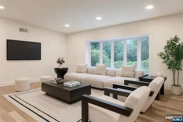 a living room with furniture a flat screen tv and a floor to ceiling window
