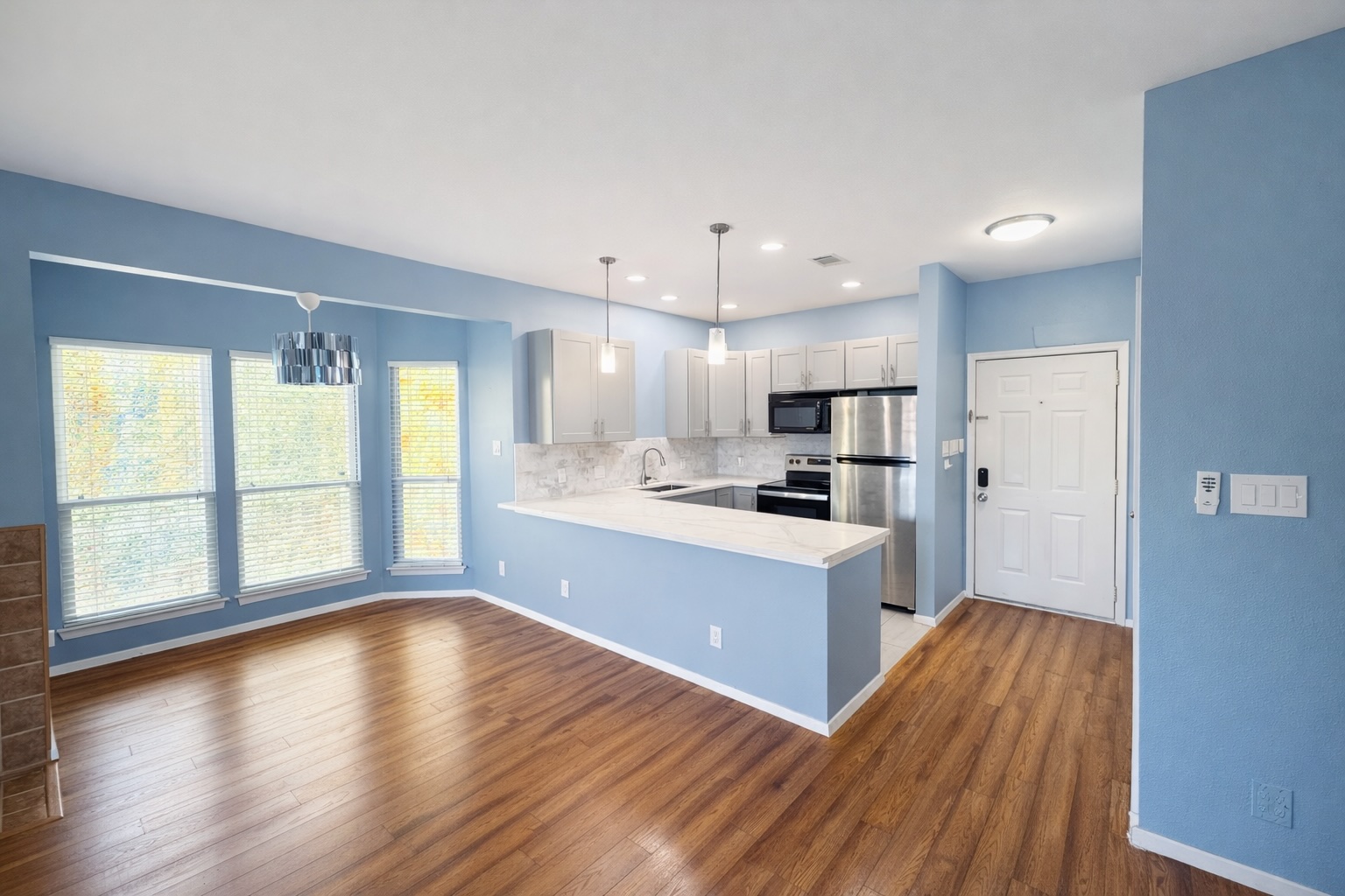 a large kitchen with cabinets wooden floor and a window