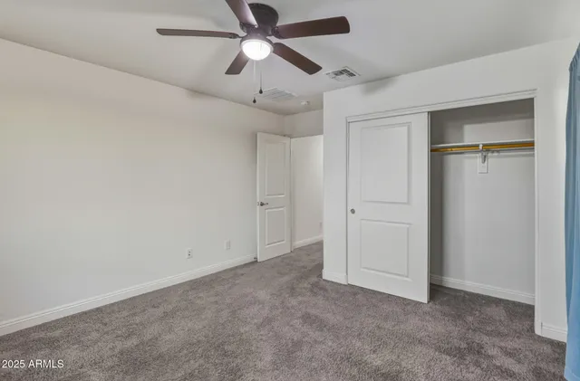 an empty room with closet and a chandelier fan