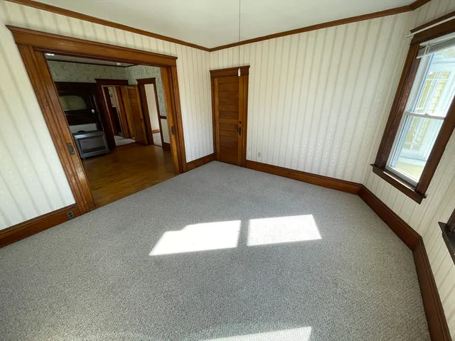 a view of an empty room with window and wooden floor