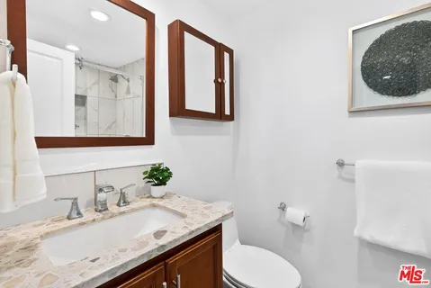 a bathroom with a granite countertop sink mirror and toilet