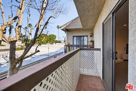 a view of a balcony with wooden floor and a large tree