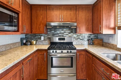 a kitchen with granite countertop a stove top oven microwave oven cabinets and a counter space